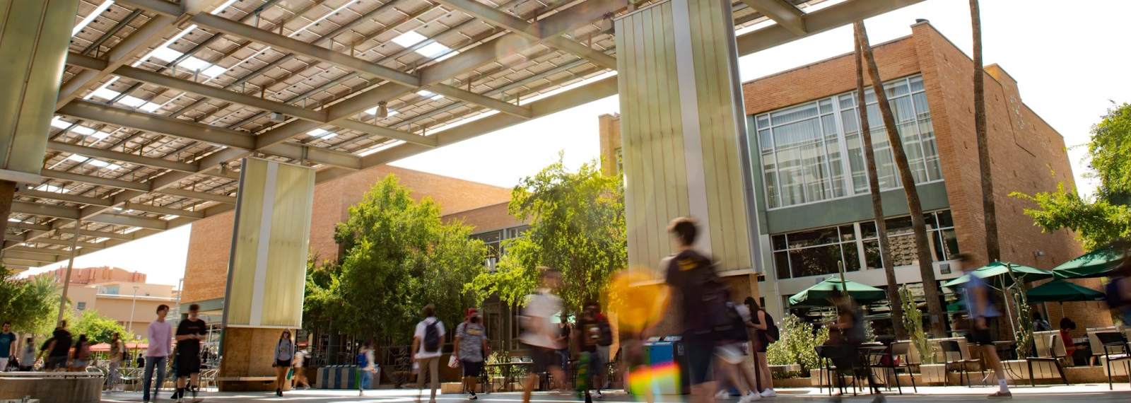 Students are walking through a common area on campus. Some are moving so fast, they are blurred. 