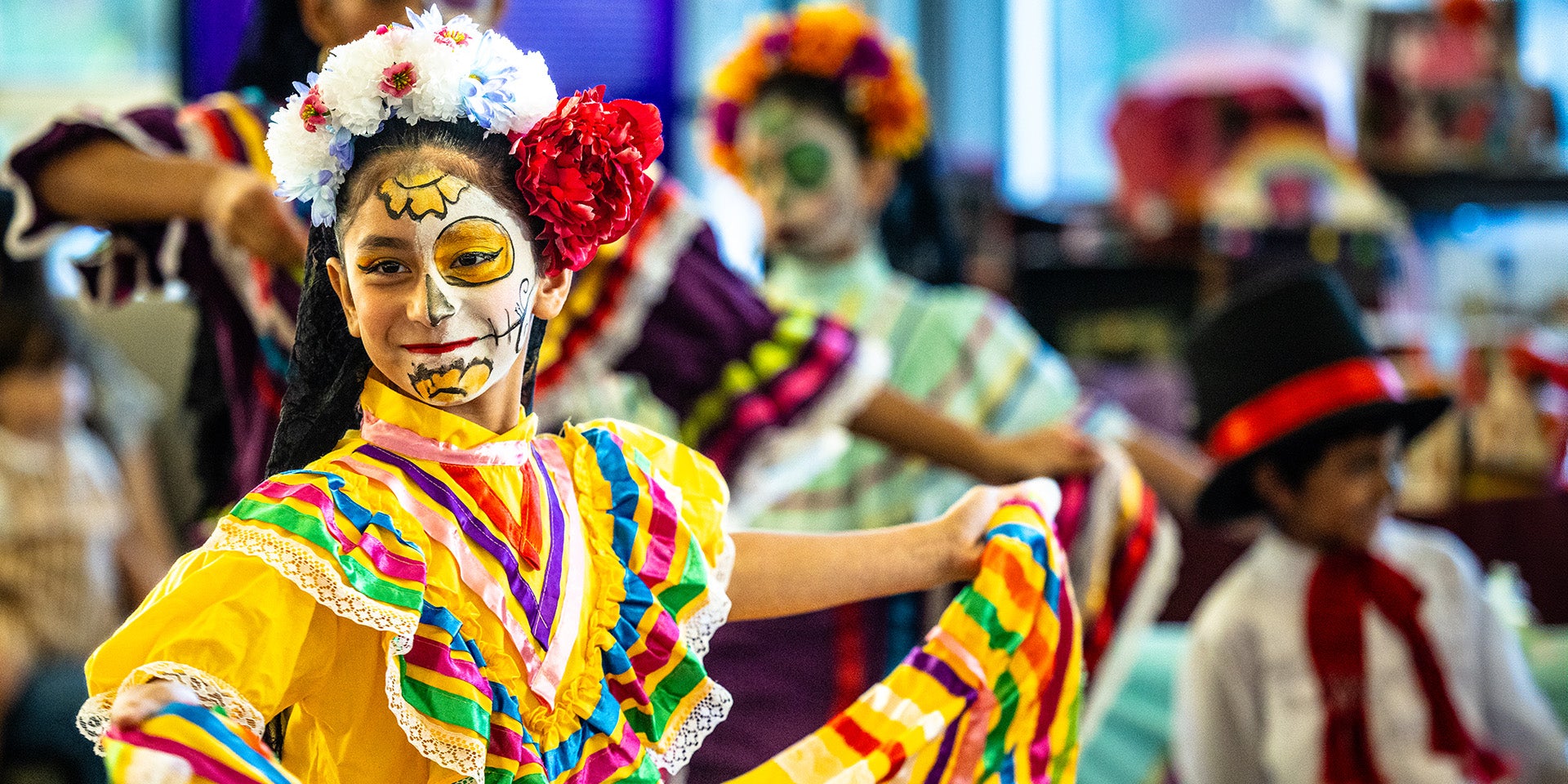 A person in a colorful outfit and Day of the Dead face paint, performing in a cultural celebration.